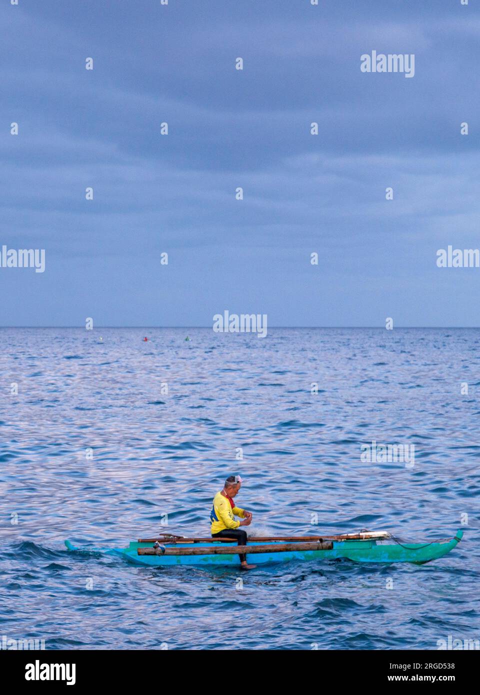 Dumaguete, Negros Island, Philippinen-Februar 01 2023: Mit einer Schutzbrille wirft der Mann relativ große Netze und taucht für Fische in der Dämmerung ins Wasser. Stockfoto