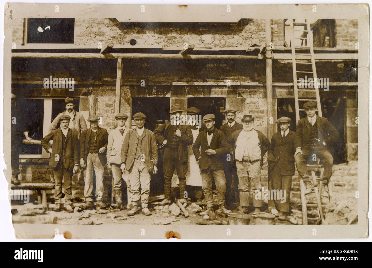Gruppenfoto einer Gruppe von Männern vor einem teilweise errichteten Haus. Beachten Sie den älteren Herrn von rechts, dessen Kleidung etwa auf 1870er/1880er datiert. Stockfoto