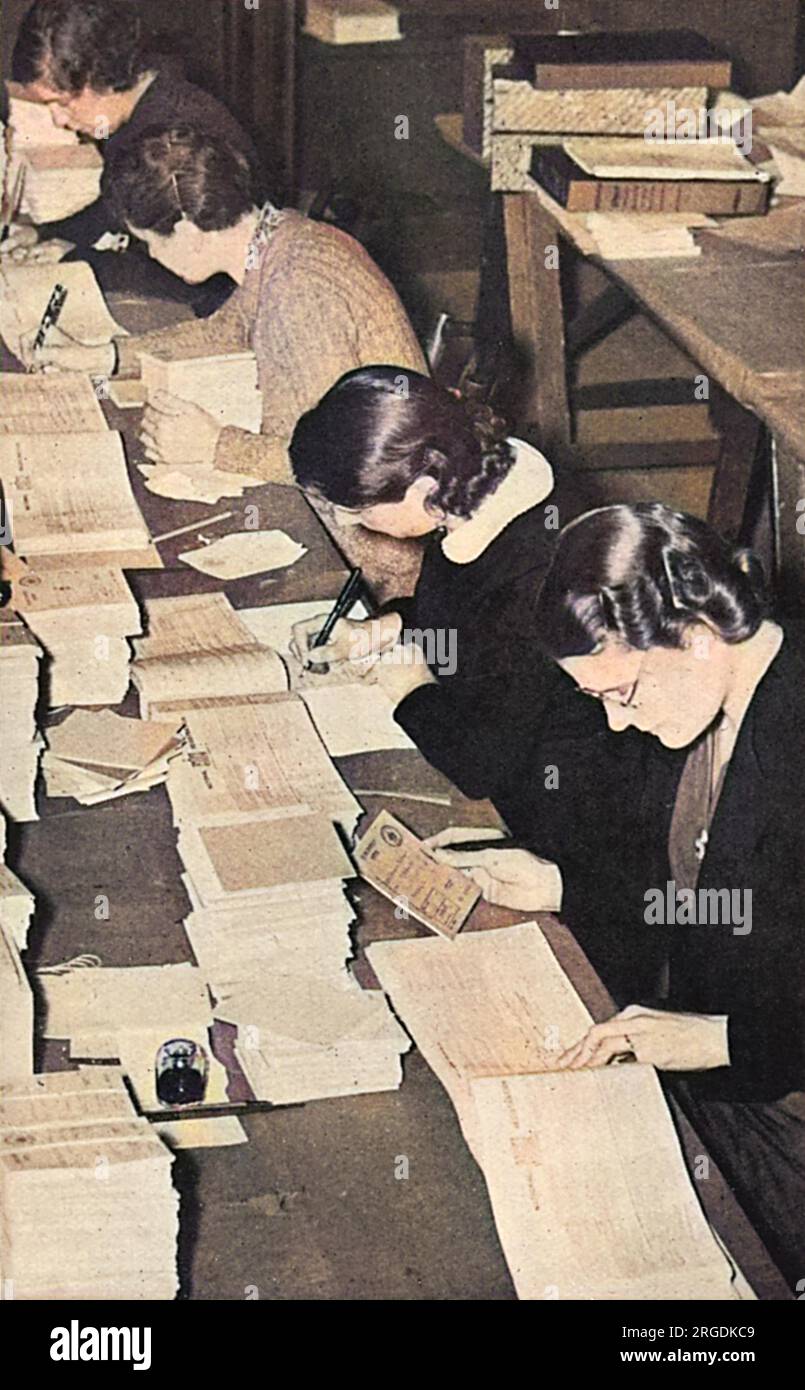 Mädchen, die damit beschäftigt waren, die Rationsbücher mit Namen und anderen Informationen auszufüllen, bevor sie 1939 an die britische Bevölkerung verteilt wurden. Stockfoto