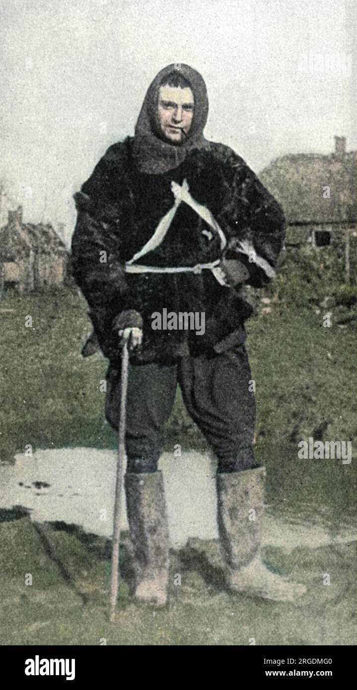 Captain Bruce Bairnsfather (1888-1959), britischer Soldat und Karikaturist, berühmt für seine Karikaturen, Fragmente aus Frankreich genannt, die im Ersten Weltkrieg im Zuschauermagazin veröffentlicht wurden und in denen mürrische und urmuddelige Soldaten zu sehen waren, einschließlich seiner Erschaffung, Old Bill. Bairnsfather ist an der Front abgebildet, „etwa eine Viertelmeile von den deutschen Gräben entfernt“ und trägt einen Pelzmantel, einen Balaclava-Helm und Gummistiefel. Direkt hinter ihm ist ein Muschelloch, das von einer Jack-Johnson-Muschel gemacht wurde. Das Foto wurde in der Gegenwart gezeigt, als die Originalgemälde für Fragmente aus Frankreich ausgestrahlt wurden Stockfoto