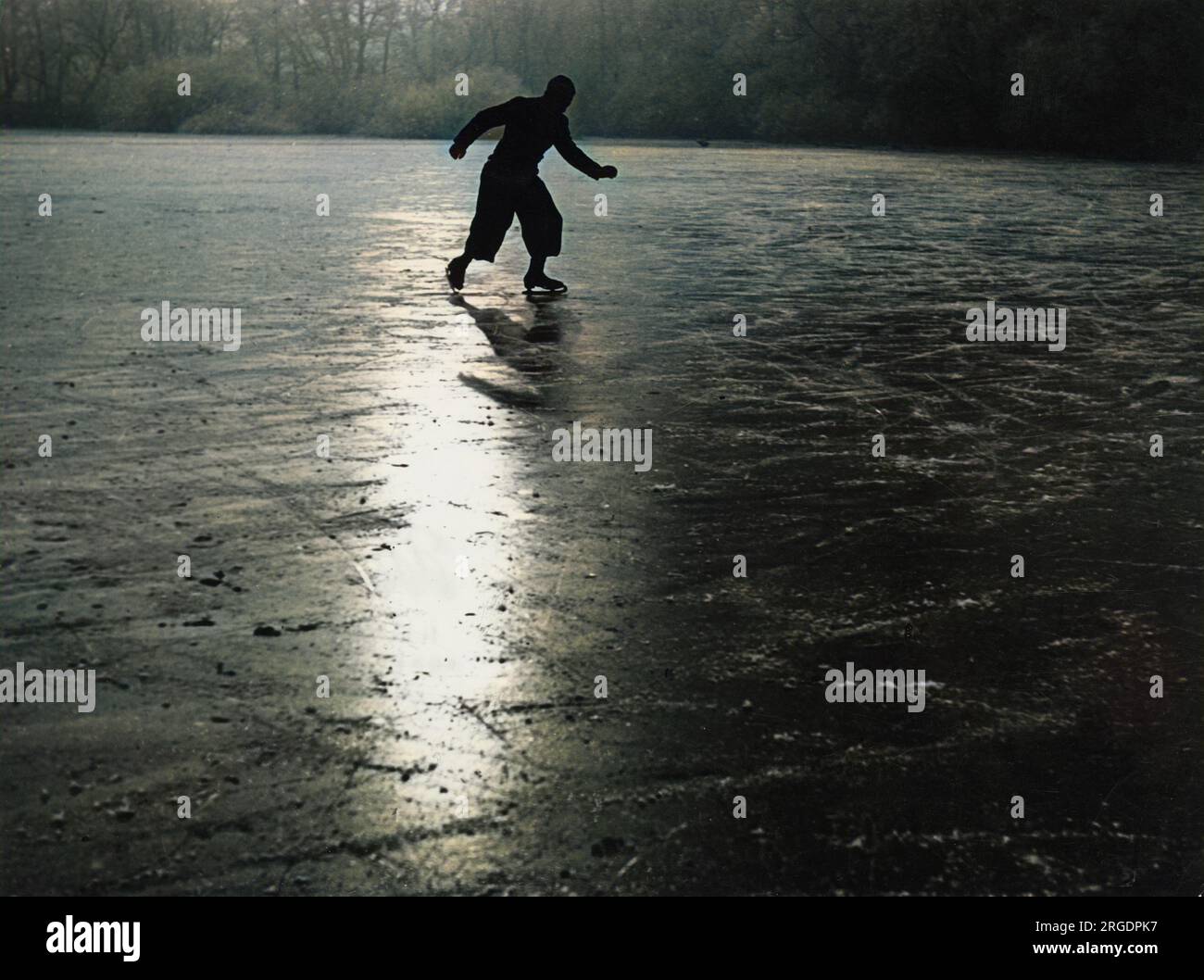 Ein einsamer Eisläufer, der Muster auf dem Eis eines gefrorenen Flusses macht. Stockfoto