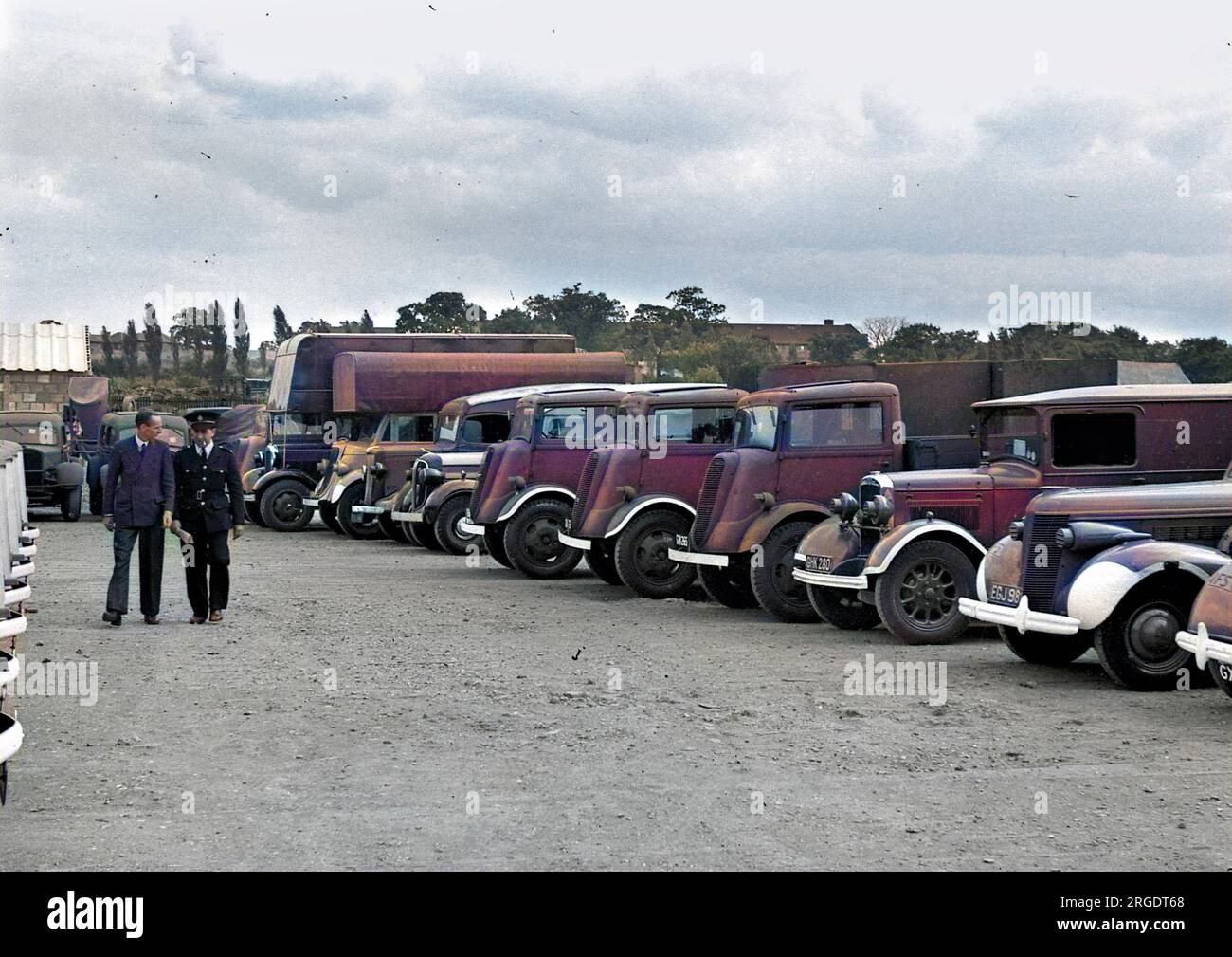 Zwei Männer auf einem Parkplatz, mit Lastwagen, Autos und Lieferwagen. Stockfoto