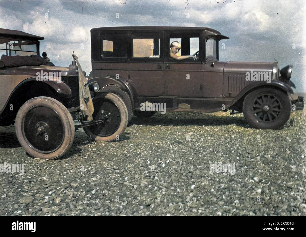 Eine Frau, die in einem Auto auf Kieselboden sitzt. Stockfoto