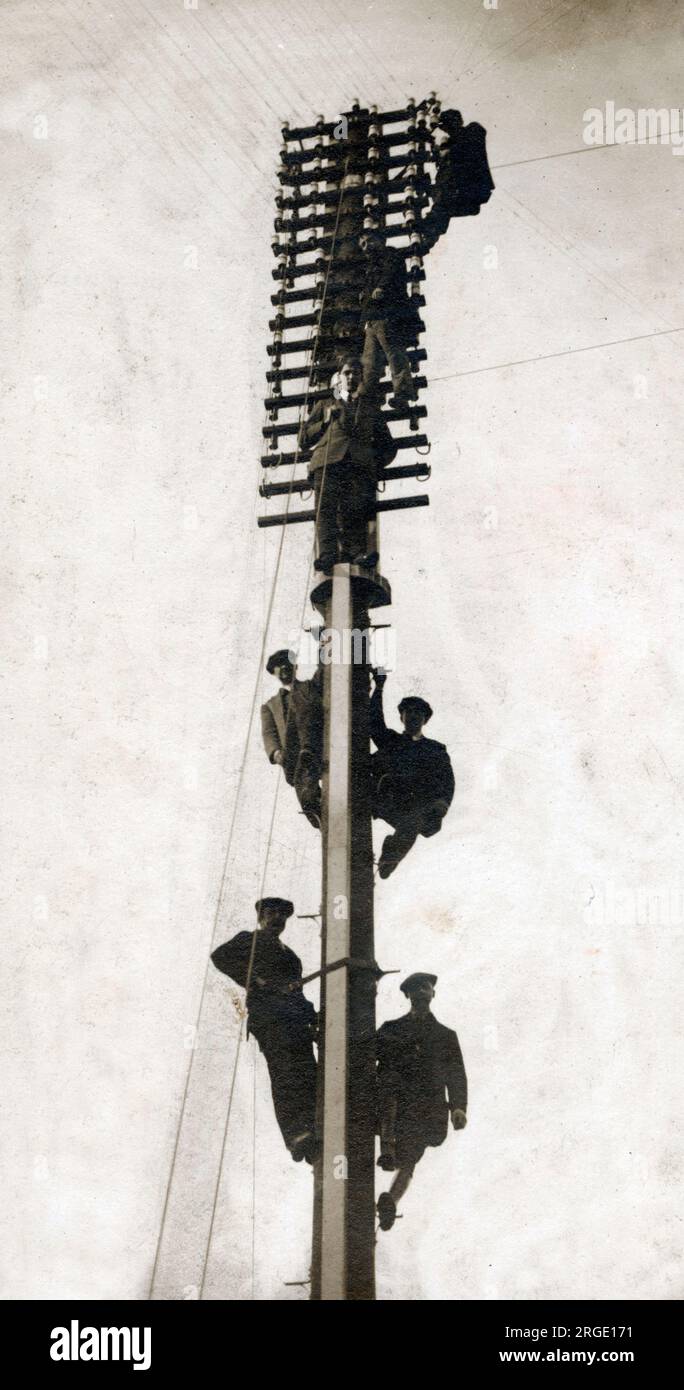Sieben Telekommunikationsingenieure installieren einen neuen Telegrafenmast. Stockfoto