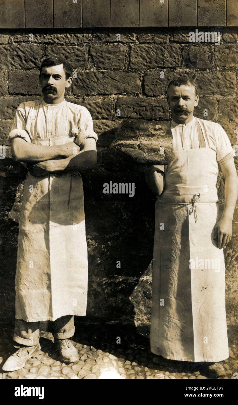 Ein Paar robuste britische Bäcker, einer mit einem großen Laib Brot. Stockfoto