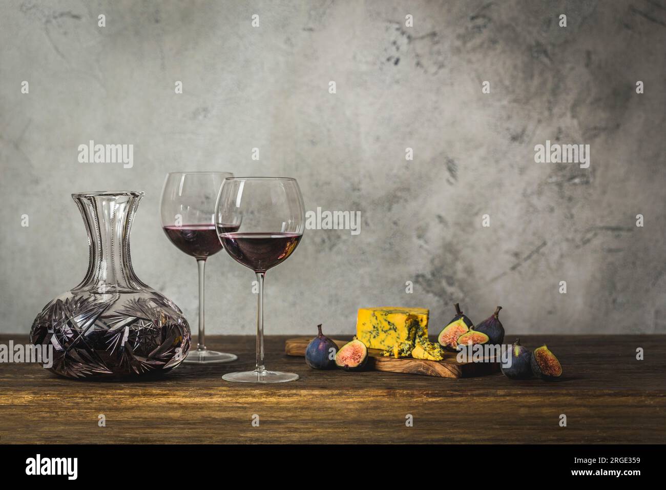 Rotwein in zwei Stängelgläsern und Kristallkaraffe mit Blaukäse und Feigen Stockfoto