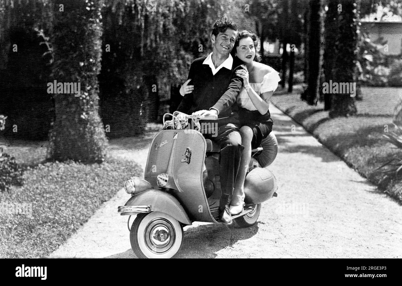 Ein junges Paar auf einer Vespa Motorroller – die Maschine, deren glamouröses Image eine der beliebten Ikonen des Jahrzehnts ist, ein Symbol für Freiheit und Jugend. Stockfoto