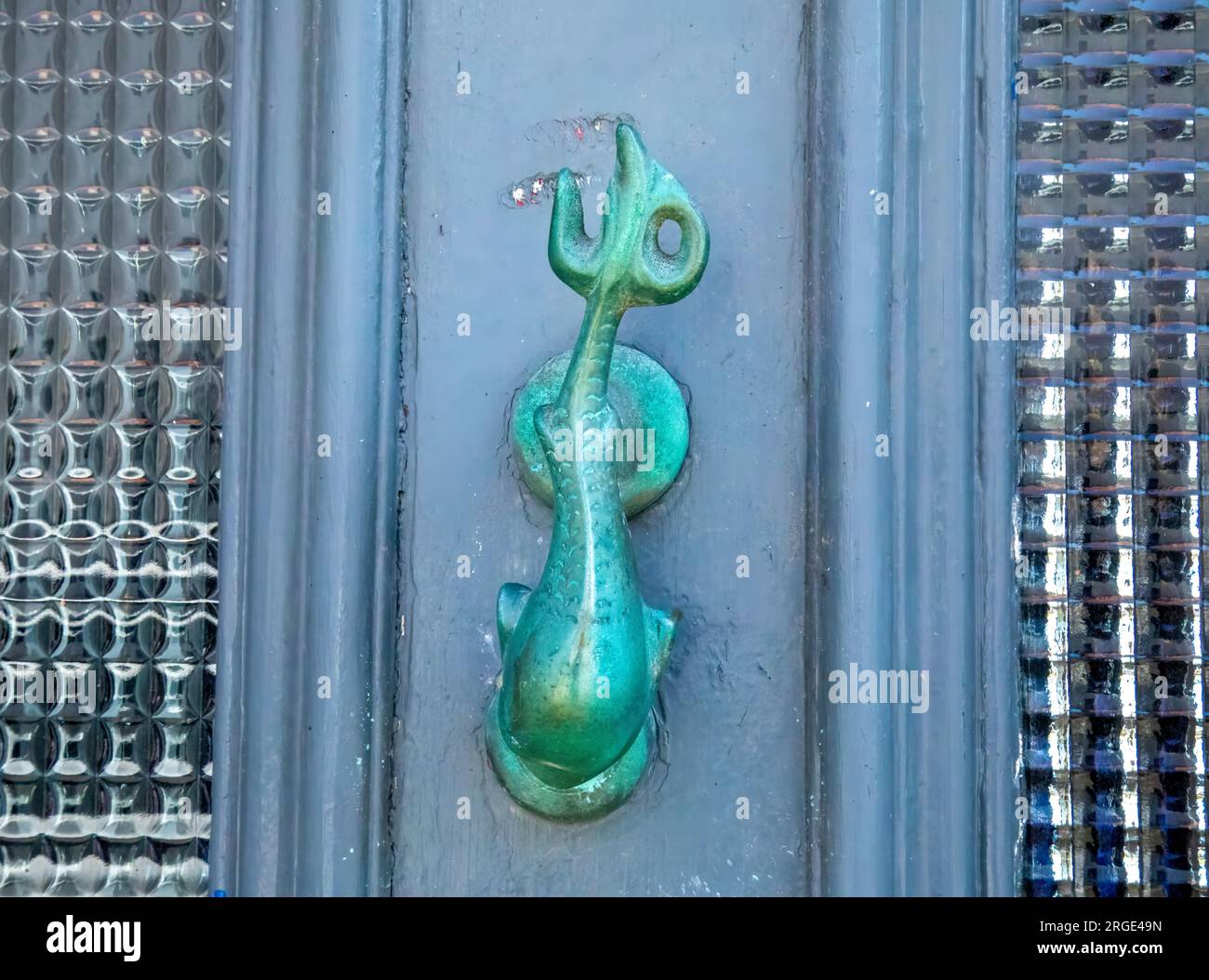 Ein Türklopfer aus Messing zeigt ein nautisches Thema eines Delfins an einer Haustür in einer Küstenstadt Stockfoto