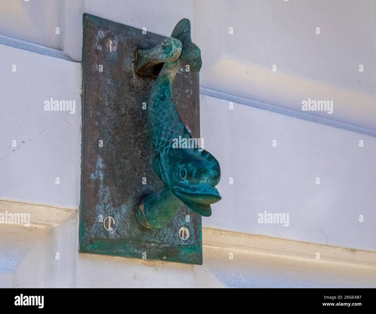 Ein Türklopfer aus Messing zeigt ein nautisches Thema eines Delfins an einer Haustür in einer Küstenstadt Stockfoto