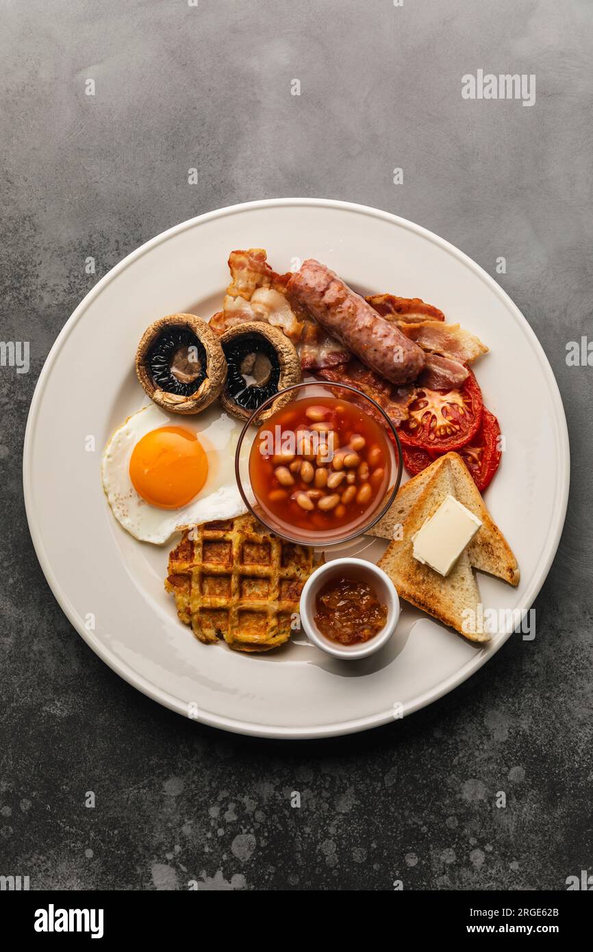 Komplettes englisches Frühstück mit Spiegeleiern, Würstchen, Speck, Bohnen, Toast Stockfoto