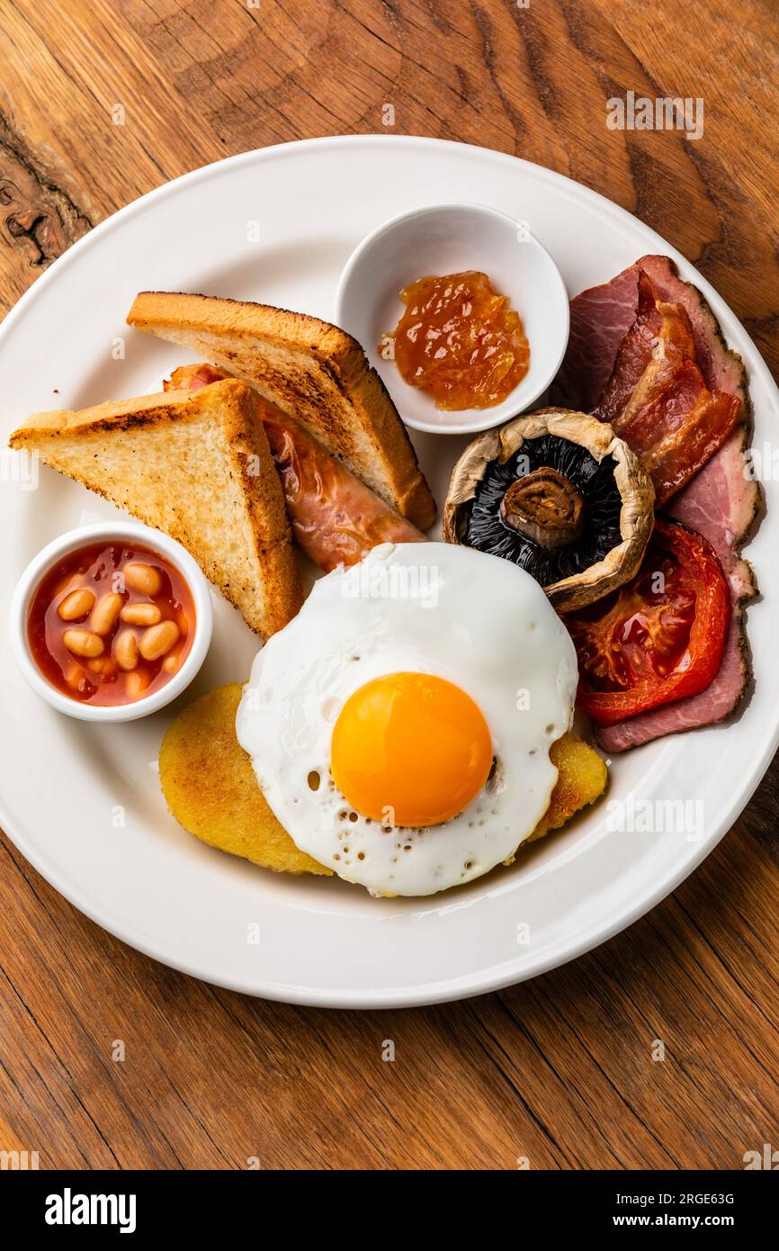 Komplettes englisches Frühstück mit Spiegeleiern, Würstchen, Speck, Bohnen, Toast Stockfoto