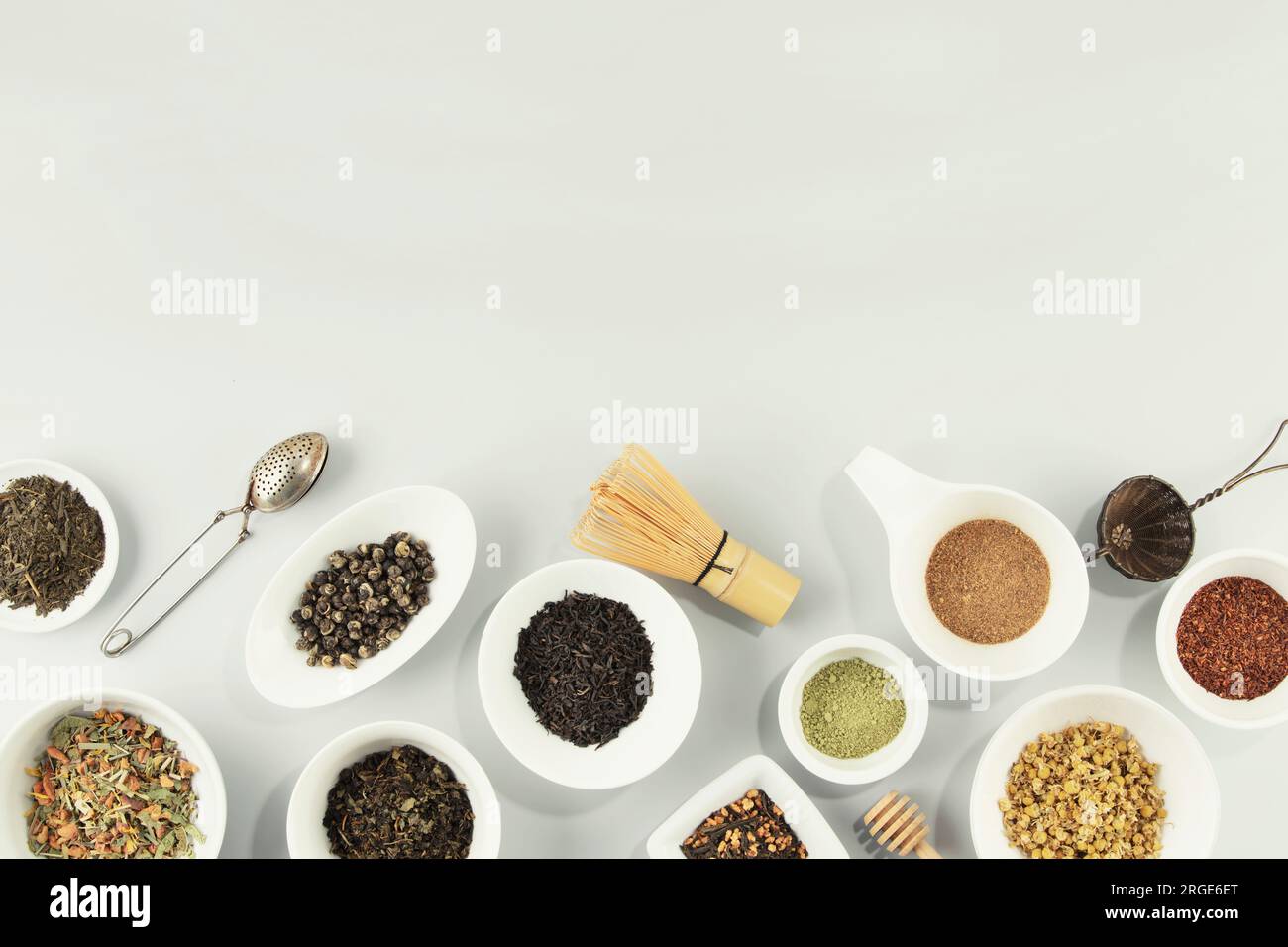 Auswahl an trockenem Tee in weißen Keramikschüsseln. Matcha, Rooibos, schwarz, grün, Kräutermischung, masala und Kamillentee. Draufsicht, flach liegend, Kopierraum für m Stockfoto