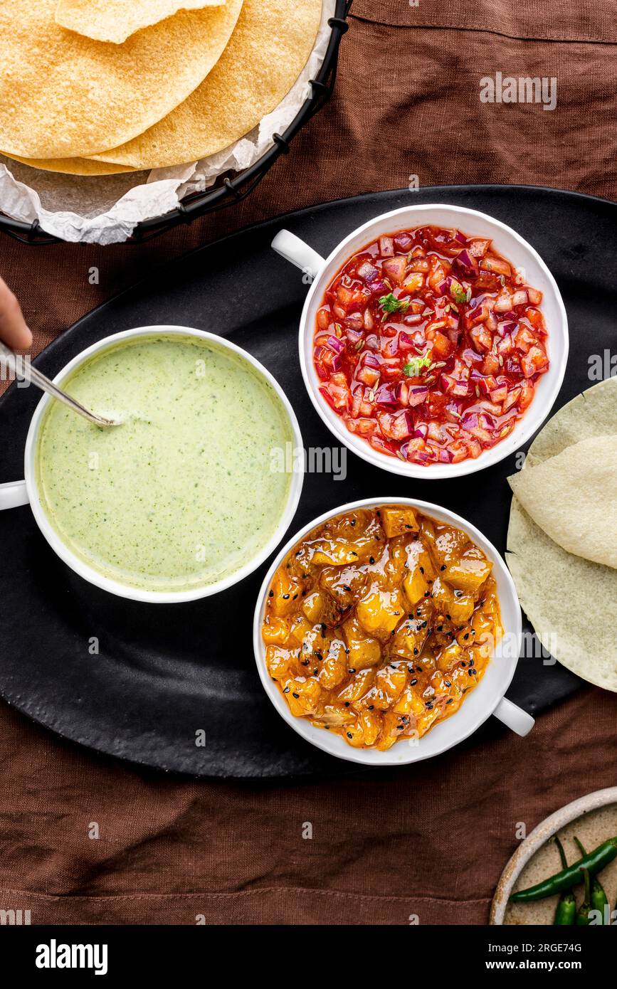 Drei Poppadom Dips: Minzjoghurtsauce, Chutney mit roten Zwiebeln, Mango-Chutney serviert mit Poppadomen Stockfoto
