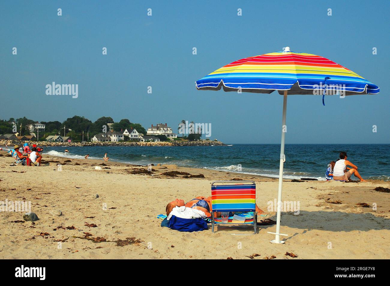 Ein farbenfroher Regenschirm steht immer noch, während die Sommerurlaube an der Küste dünn wird Stockfoto