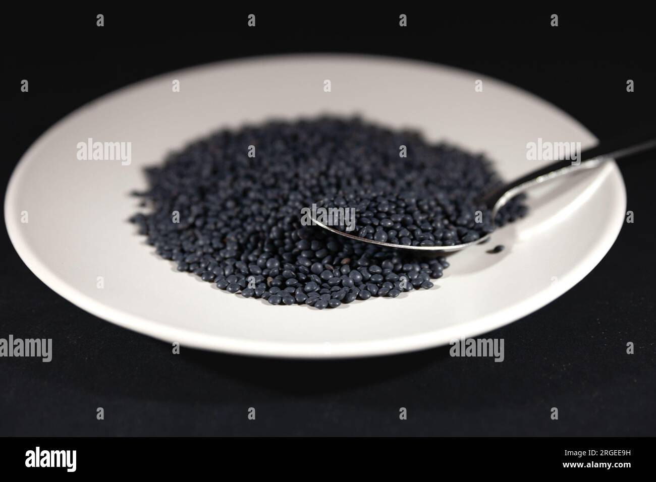 Bild von schwarzen Linsen vom Typ Beluga-Linsen auf einem Schild. Die Linse (Lens culinaris oder Lens esculenta) ist eine essbare Hülse. Es ist ein Stockfoto