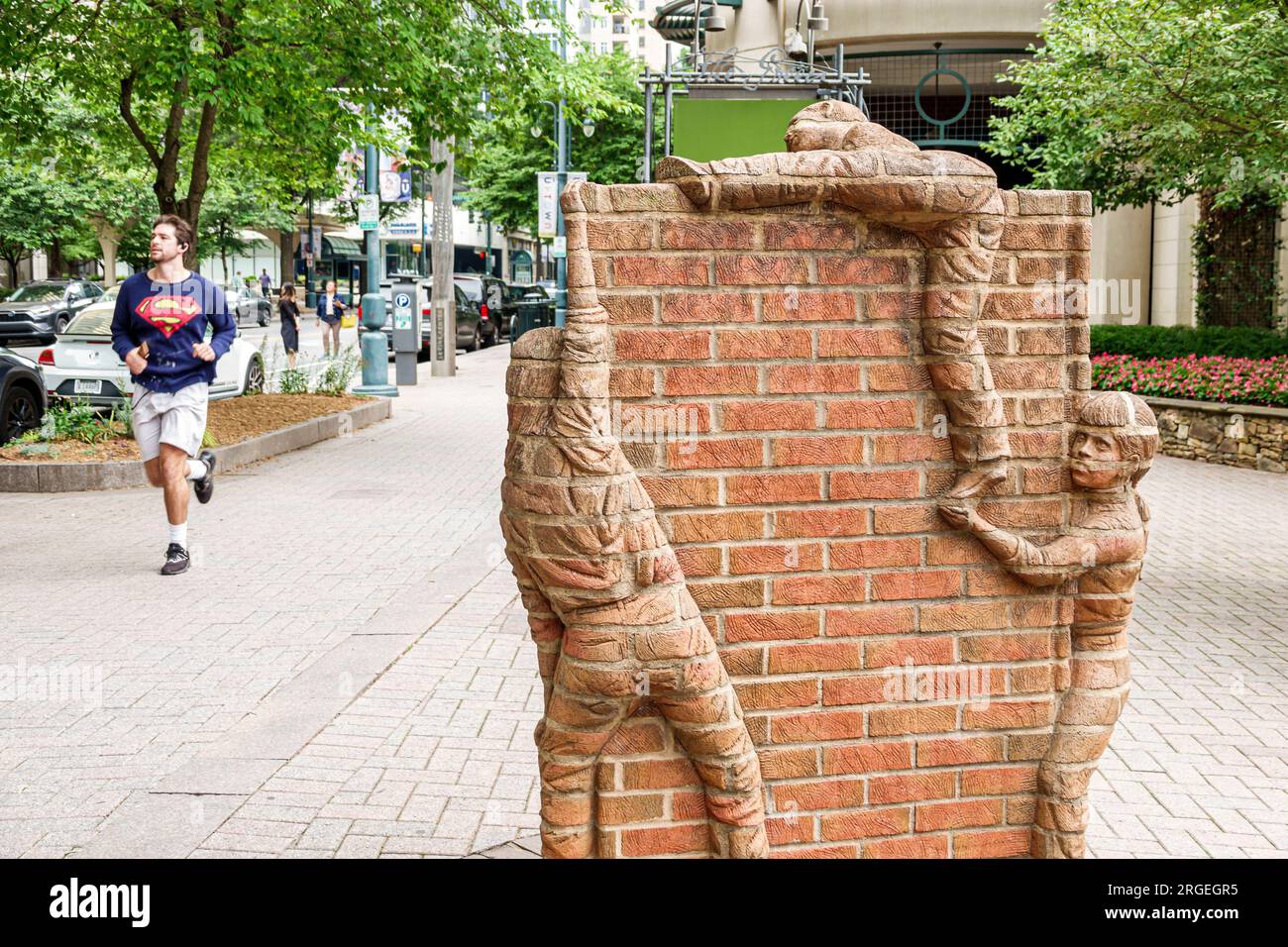 Charlotte North Carolina, South Tryon Street, öffentliche Kunstwerke Skulpturen Jungen klettern Ziegelmauern, Männer männlich, Erwachsener, Bewohner, Jogger Jogging Stockfoto