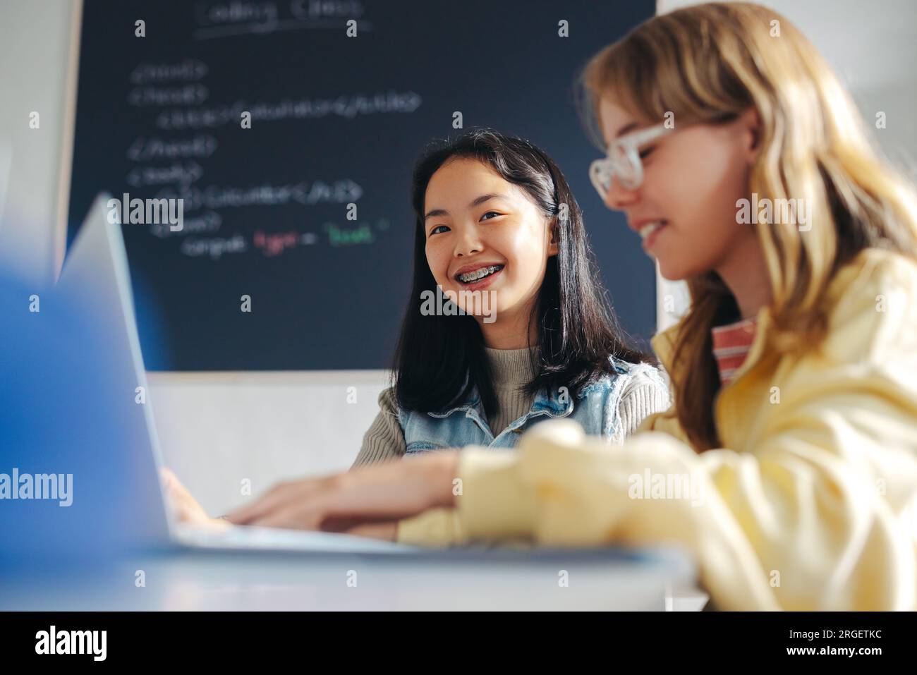 Mädchen sitzen zusammen, während sie Programmierung und Programmierung in einem Klassenzimmer der Computerakademie lernen. Junge Studentinnen, die gerne ihr digitales Licht bauen Stockfoto