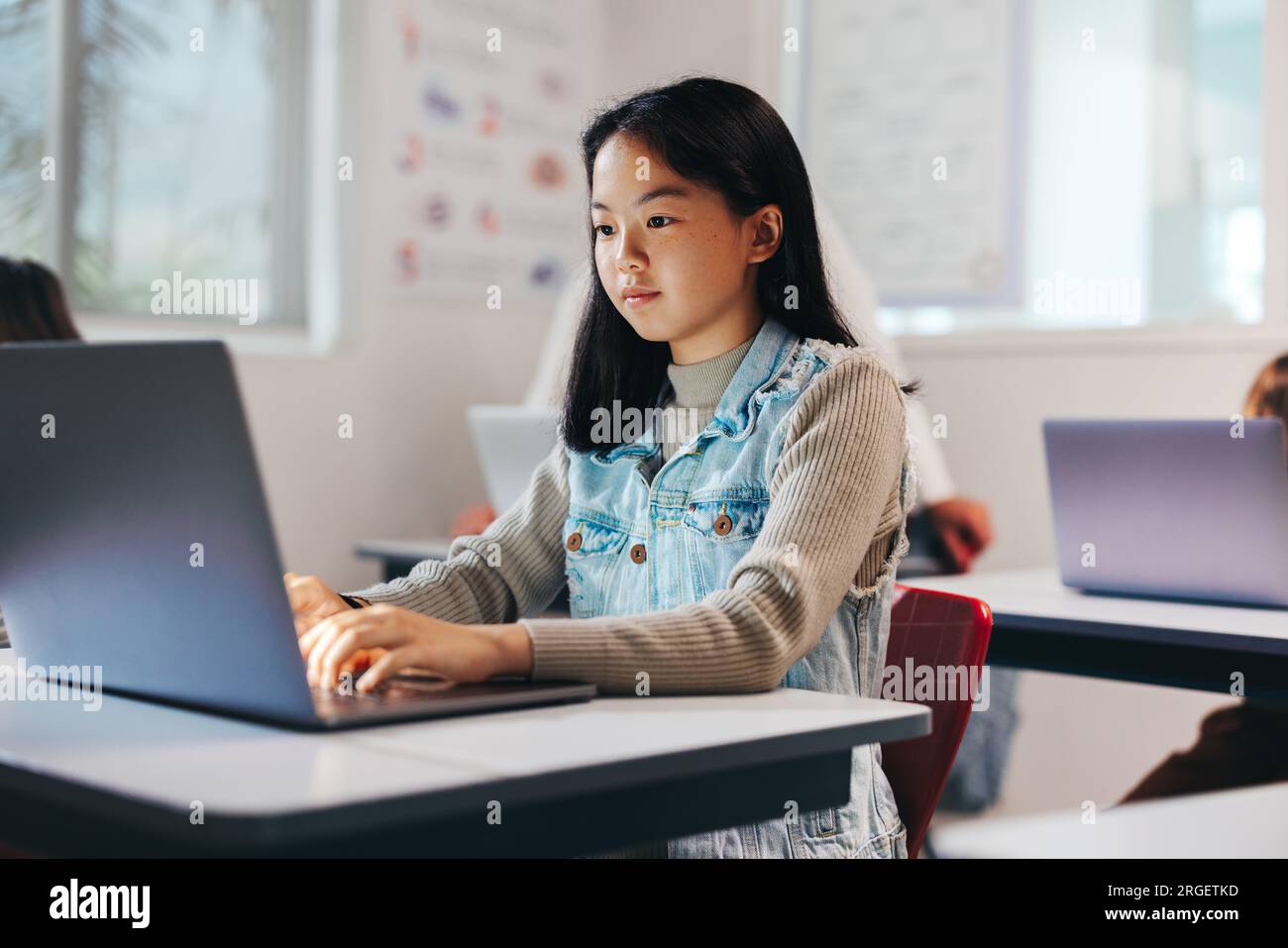 Das junge Mädchen arbeitet in einem Klassenzimmer an einer Computerprogrammierung und erkundet die digitale Welt mit ihren neu erworbenen Programmierkenntnissen. Weibliches Kind si Stockfoto