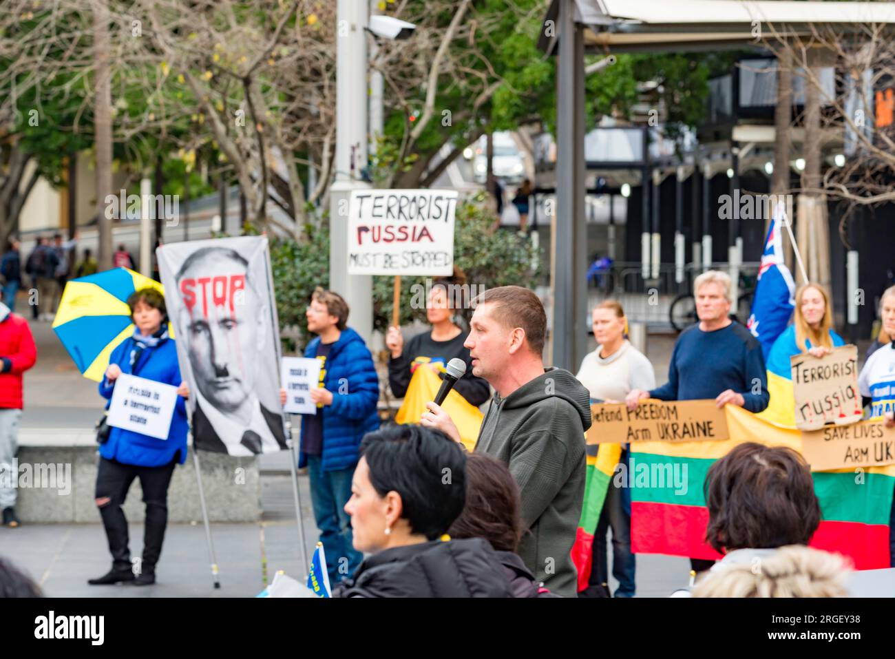 Demonstranten an einem Pro-Ukraine-Rallye-Stand mit den blauen und gelben Nationalfarben, mit litauischen Flaggen und einem blutbedeckten Poster von Wladimir Putin Stockfoto