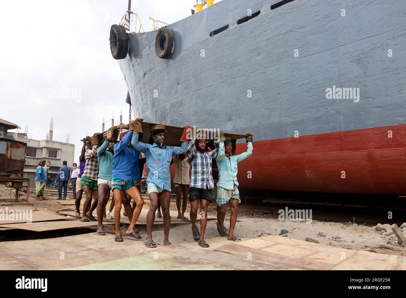 Dhaka, Dhaka, Bangladesch. 9. Aug. 2023. Eine Gruppe von Gepäckträgern trägt eine schwere Stahlplatte von 250 kg auf einer Werft am Ufer des Buriganga in Keraniganj, nahe Dhaka, Bangladesch. Dutzende von Werften, die 30,96 Hektar an der Küste von Buriganga belegen, sind seit 50 Jahren in Betrieb. Es wird hauptsächlich zur Reparatur und Reparatur alter Schiffe und zum Bau neuer Schiffe verwendet. Die Arbeit auf dem Werftplatz funktioniert ohne Helme, Gesichtsmasken oder Sicherheitsschuhe. Sie arbeiten den ganzen Tag lang hart, erhalten aber trotzdem Mindestlöhne. Mit einer zunehmenden Anzahl von Bestellungen sowohl von lokalen als auch von globalen Käufern, ist der Schiffbauer Stockfoto