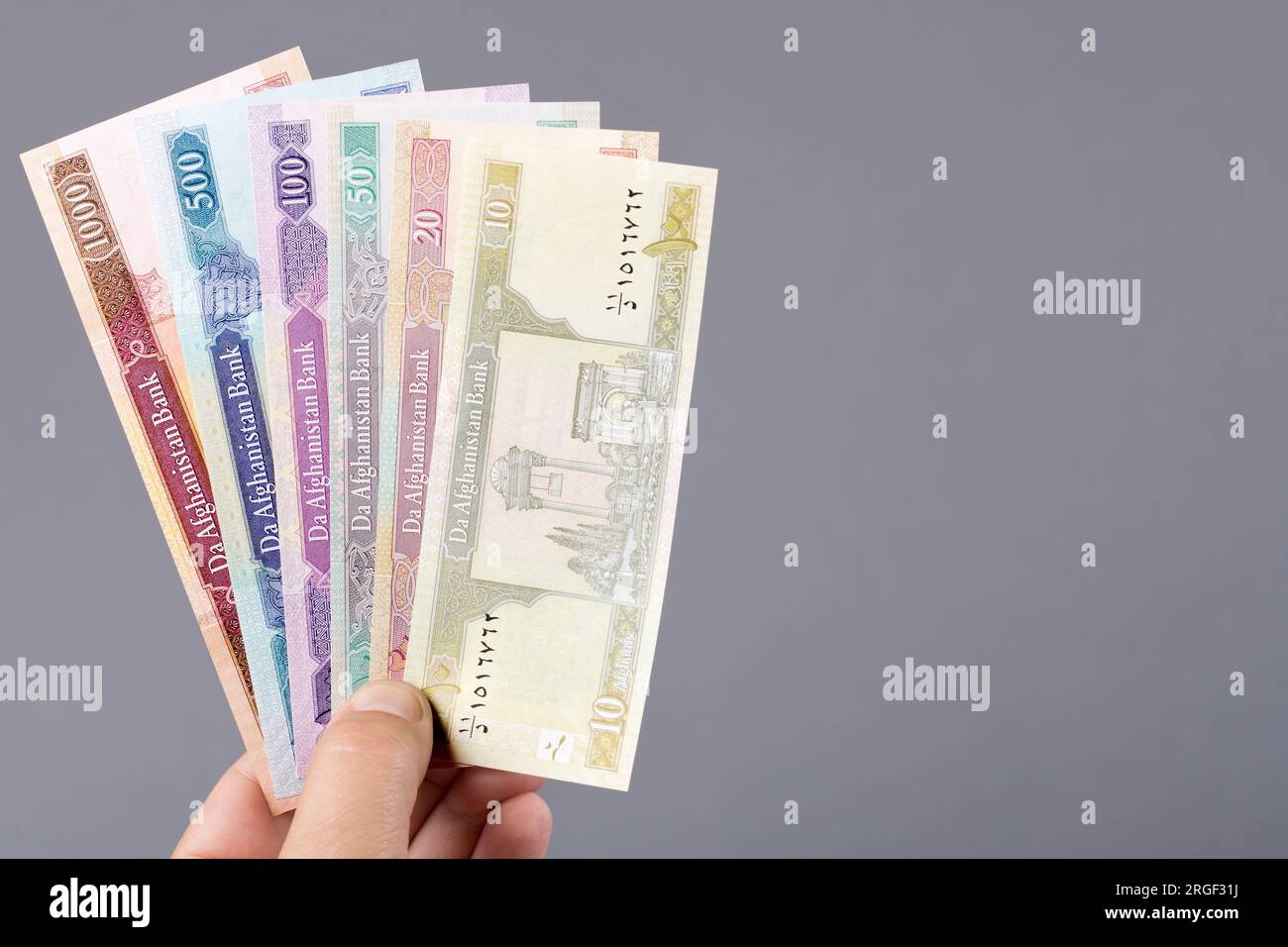 Altes afghanisches Geld - afghani in der Hand auf grauem Hintergrund Stockfoto