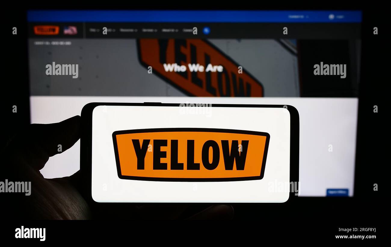 Person, die ein Mobiltelefon mit dem Logo des US-Logistikunternehmens Yellow Corporation auf dem Bildschirm vor der Unternehmenswebseite hält. Konzentrieren Sie sich auf das Display des Telefons. Stockfoto
