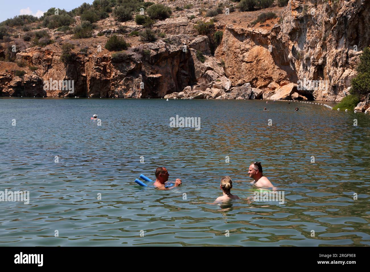 Vouliagmeni Athen griechische Touristen Schwimmen im See Vouliagmeni ein Naturbad - war einst eine Höhle, aber das Höhlendach fiel durch Erosion aus der hinein Stockfoto