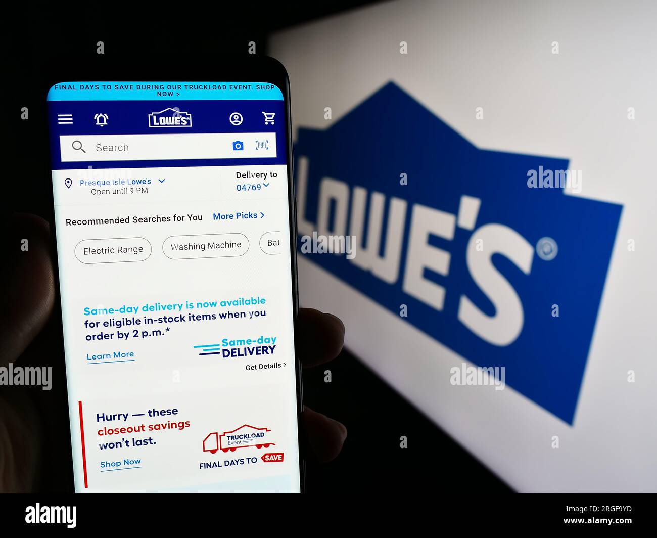 Person, die ein Smartphone mit einer Webseite des US-amerikanischen Einzelhandelsunternehmens Lowe's Companies Inc. Auf dem Bildschirm vor dem Logo hält. Konzentrieren Sie sich auf die Mitte des Telefondisplays. Stockfoto