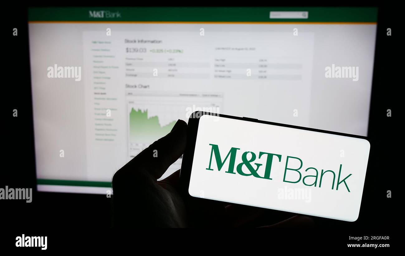 Person, die ein Mobiltelefon mit dem Logo des amerikanischen Finanzunternehmens MT Bank Corporation auf dem Bildschirm vor der Webseite hält. Konzentrieren Sie sich auf das Display des Telefons. Stockfoto