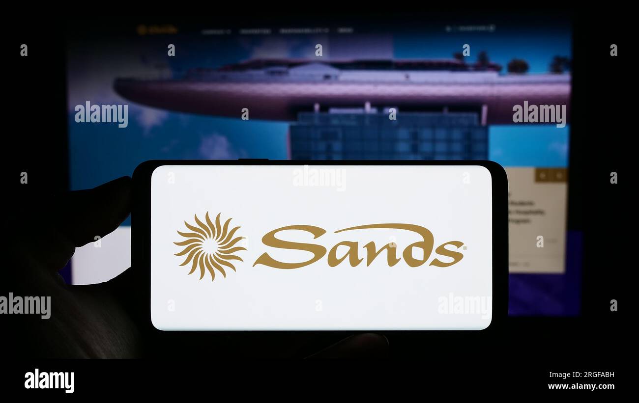 Person, die ein Handy mit dem Logo der amerikanischen Resortfirma Las Vegas Sands Corporation auf dem Bildschirm vor der Webseite hält. Konzentrieren Sie sich auf das Display des Telefons. Stockfoto