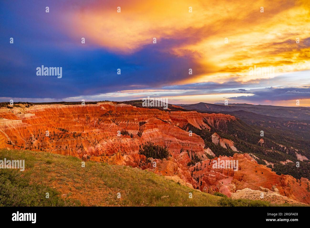 Vom Chessman Ridge Overlook of Cedar Breaks National Monument, UT, USA, blickt die untergehende Sonne auf die roten Felsenklippen und Wolken im Osten. Stockfoto