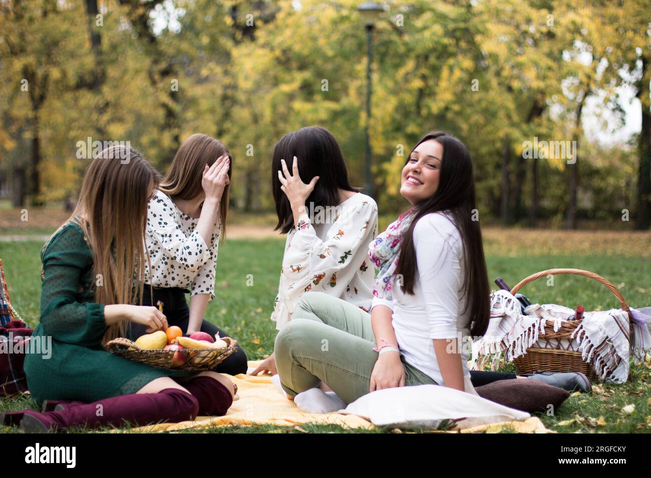 Eine Gruppe von vier Frauen auf einem lustigen Herbstpicknick im Park, mit viel Spaß. Stockfoto