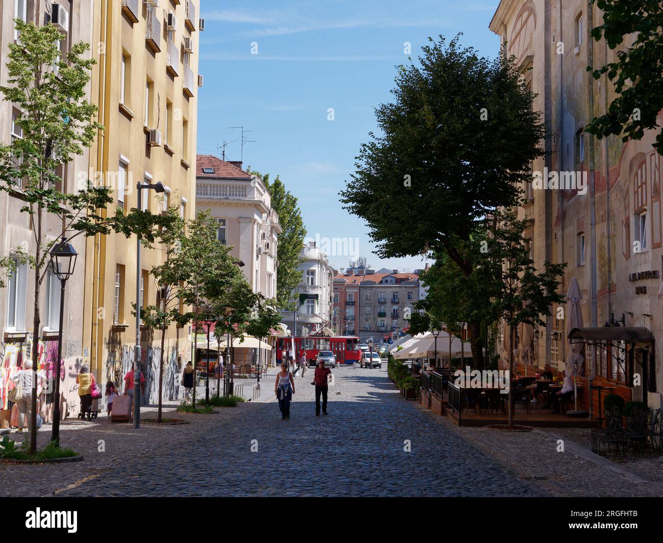 Die berühmte Bohème-Kopfsteinpflaster-Straße Skadarlija mit Cafés und Restaurants mit Straßenbahn unten in der Stadt Belgrad, Serbien. August 2023. Stockfoto