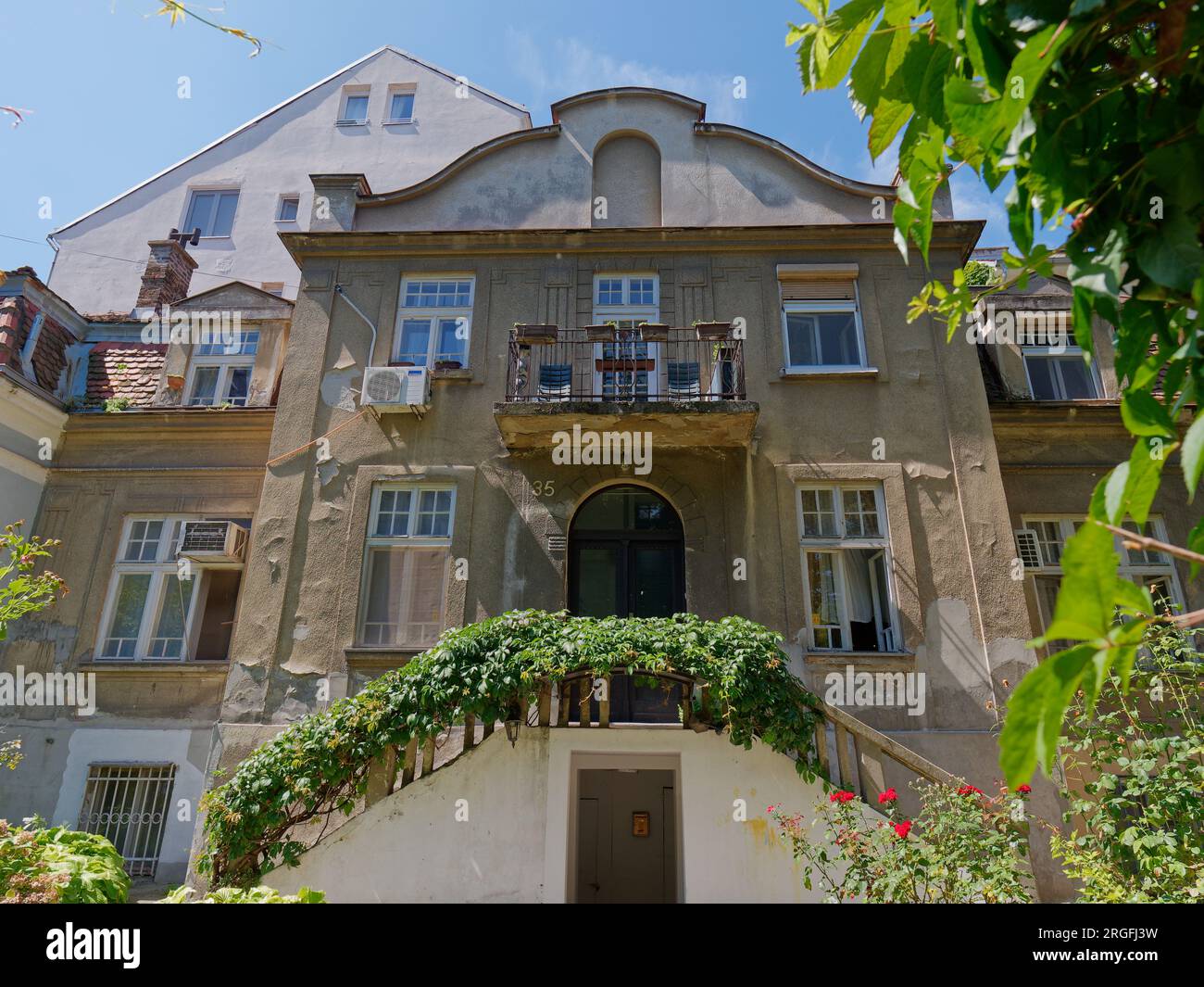 Elegantes mehrstöckiges Haus mit Balkontreppen, die zu einer erhöhten Tür in der Stadt Belgrad, Serbien, führen. August 2023. Stockfoto