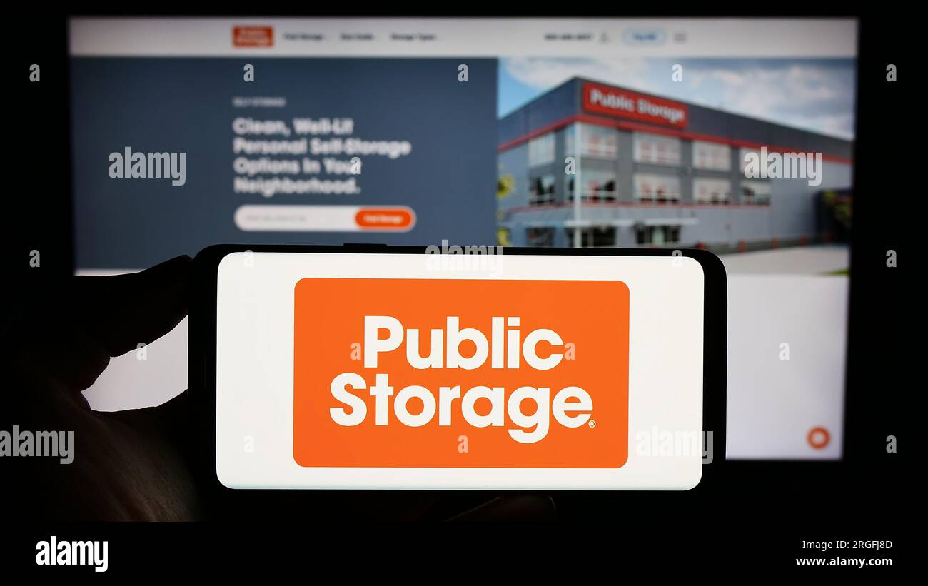 Person, die ein Mobiltelefon mit dem Logo des US-Immobilienunternehmens Public Storage auf dem Bildschirm vor der Unternehmenswebseite hält. Konzentrieren Sie sich auf das Display des Telefons. Stockfoto