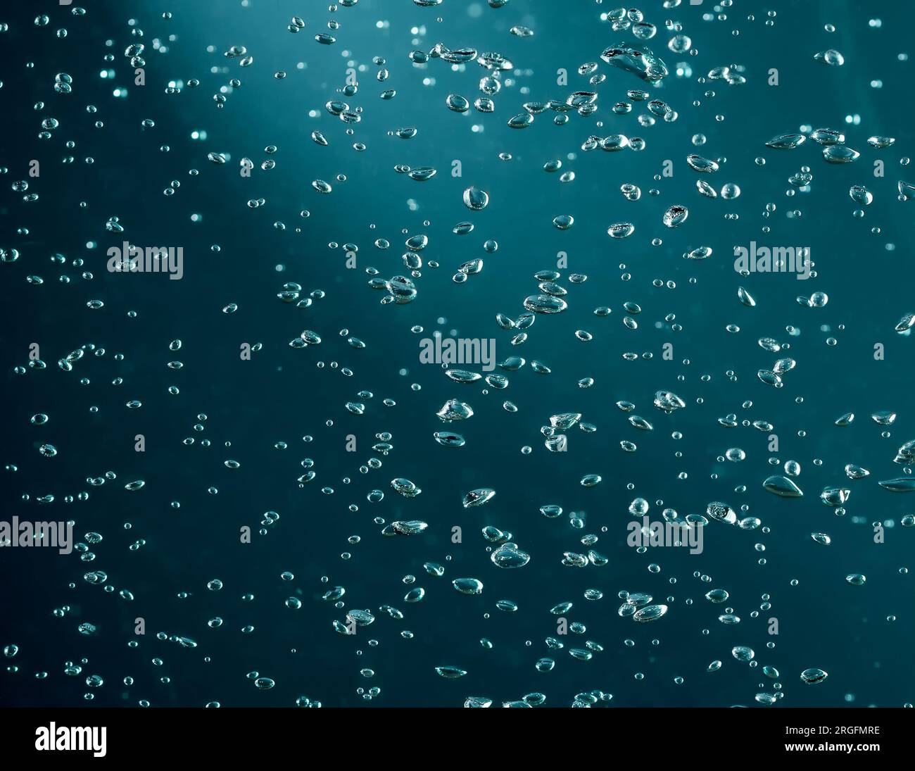 Luftblasen im Wasser auf dunkelblauem grünem Hintergrund Stockfoto