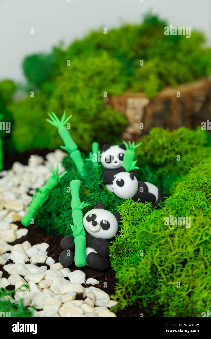 Lustige hausgemachte Plastilin-Pandas in einem stilisierten Dschungel. Konzept für Welttiertag, Panda-Tag, Erdtag. Umweltschutz. Stockfoto