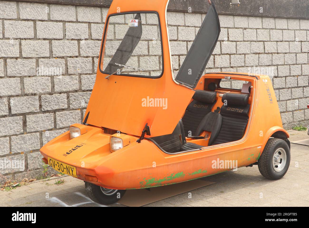 Oldtimer-Orange Bond Bug, kleines britisches dreirädriges Auto mit zwei Sitzen auf der Automesse in Lelystad, Niederlande - Juni 18 2023 Stockfoto