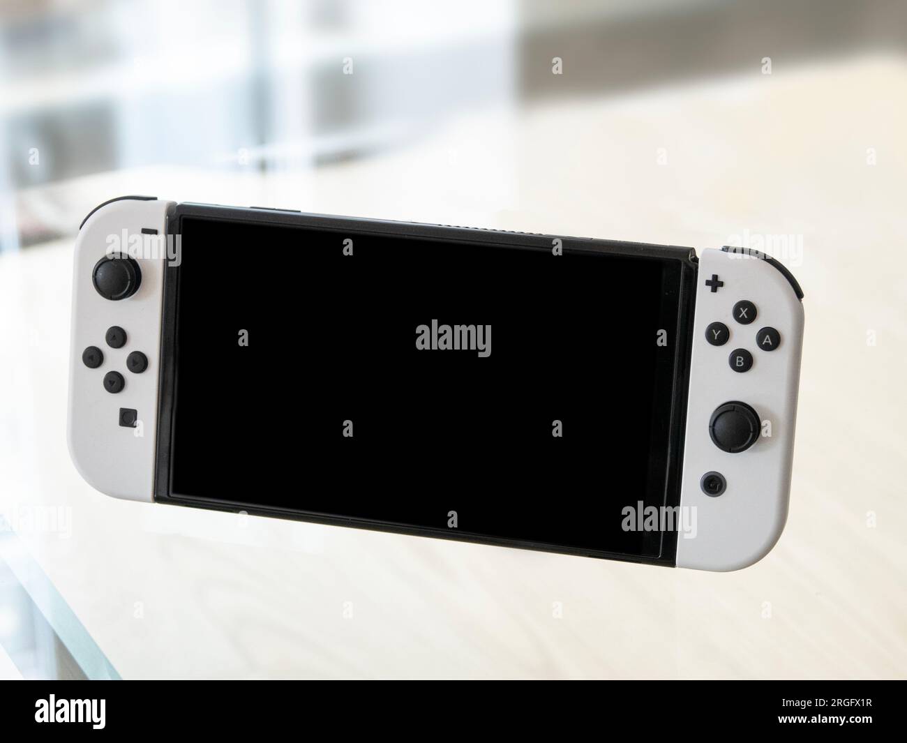 Nintendo Switch – OLED-Modell im Handbetrieb. Beliebte mobile Spielekonsole auf einer Glasplatte. Kopenhagen, Dänemark - 9. August 2023. Stockfoto