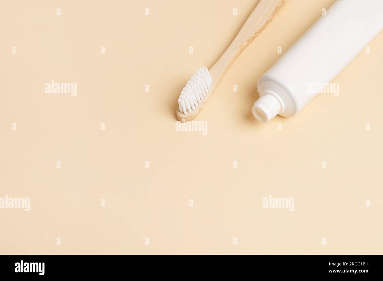 Leere weiße Tube mit Zahnpasta und Holzbürste auf beigefarbenem Hintergrund, Kopierbereich Stockfoto