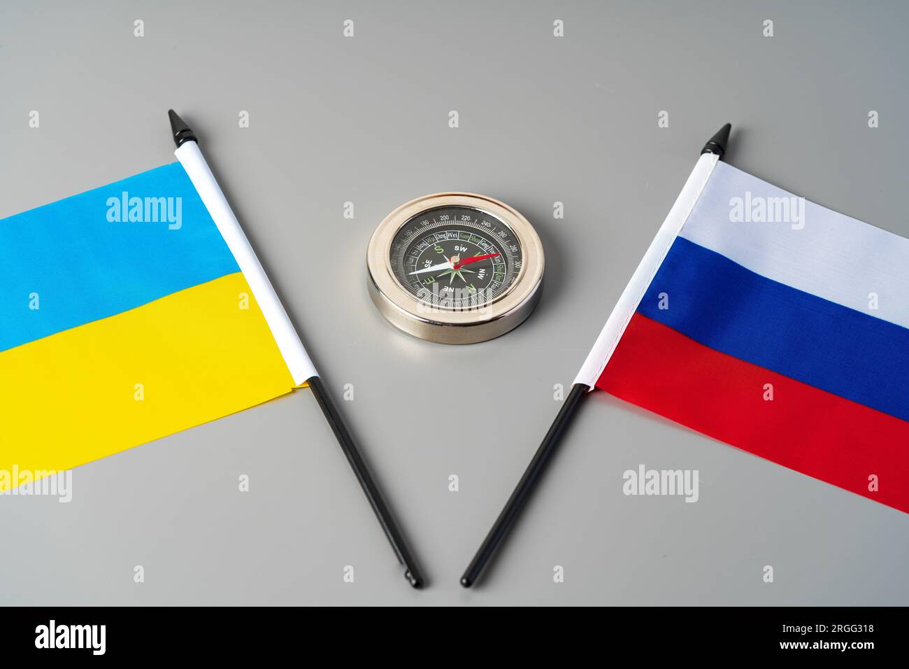 Flaggen der Ukraine und Russlands mit Kompass auf grauem Hintergrund Stockfoto
