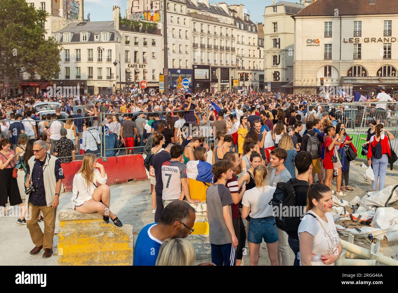 Paris, Frankreich, 2018. Eine freche Blondine sitzt auf einem Betonblock inmitten des glücklichen Chaos am Place de la Bastille, dem Tag, an dem Frankreich die Fußballweltmeisterschaft gewann Stockfoto