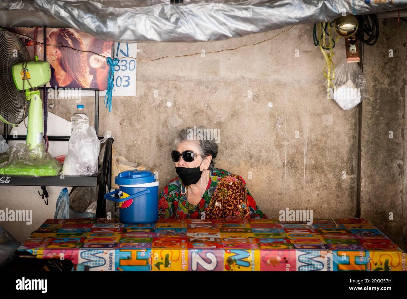 Eine alte thailändische Dame sitzt in einem thailändischen Café oder Restaurant im Freien in der Sanam Khli Alley, Bangkok, Thailand. Stockfoto