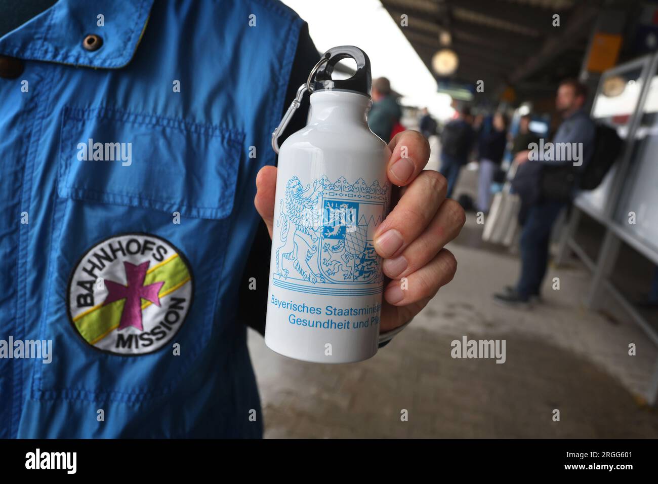 Augsburg, Deutschland. 09. Aug. 2023. Christian Müller, Facility Manager der Station Mission, zeigt eine Trinkflasche auf einem Bahnsteig am Hauptbahnhof. Auf einer Presseveranstaltung wurde ein Projekt des bayerischen Gesundheitsministeriums vorgestellt, in dem bayerische Bahnhofsmissionen mit Trinkflaschen und, falls erforderlich, Sonnencreme zur Verteilung an die Betroffenen ausgestattet werden. Kredit: Karl-Josef Hildenbrand/dpa/Alamy Live News Stockfoto