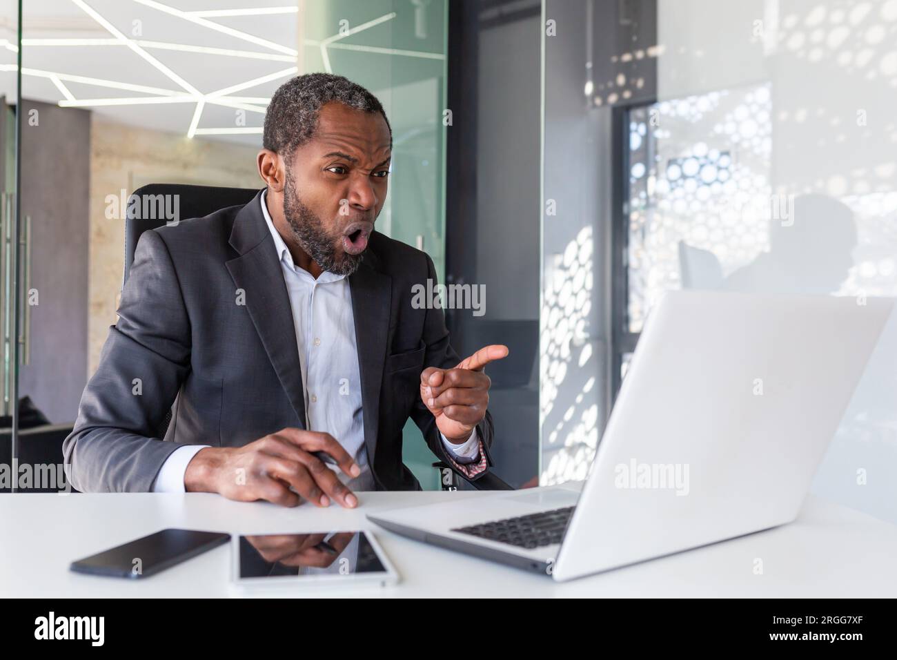 Wütender, nervöser Geschäftsmann, der per Fernzugriff per Videoanruf mit einem Laptop telefoniert, erfahrener erfahrener erfahrener erfahrener erfahrener, reifer Chef, der schreit und sich am Arbeitsplatz im Büro streitet. Stockfoto