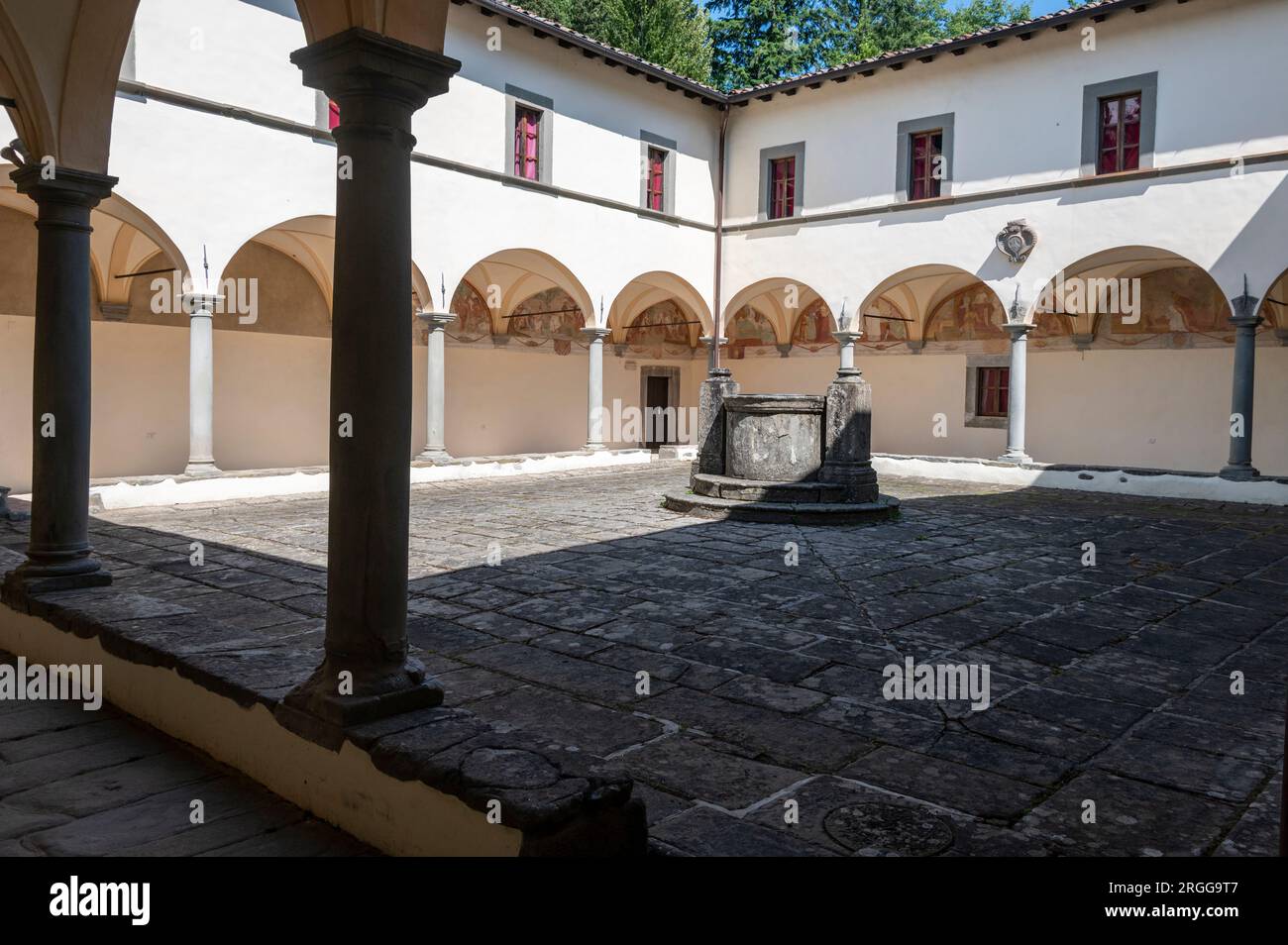Die umliegenden Klöster mit verblassten Wandmalereien, die vom lokalen Künstler Stefano Lemmi gemalt wurden, und ein zentraler Brunnen im Innenhof des restaurierten Convento del Ca Stockfoto