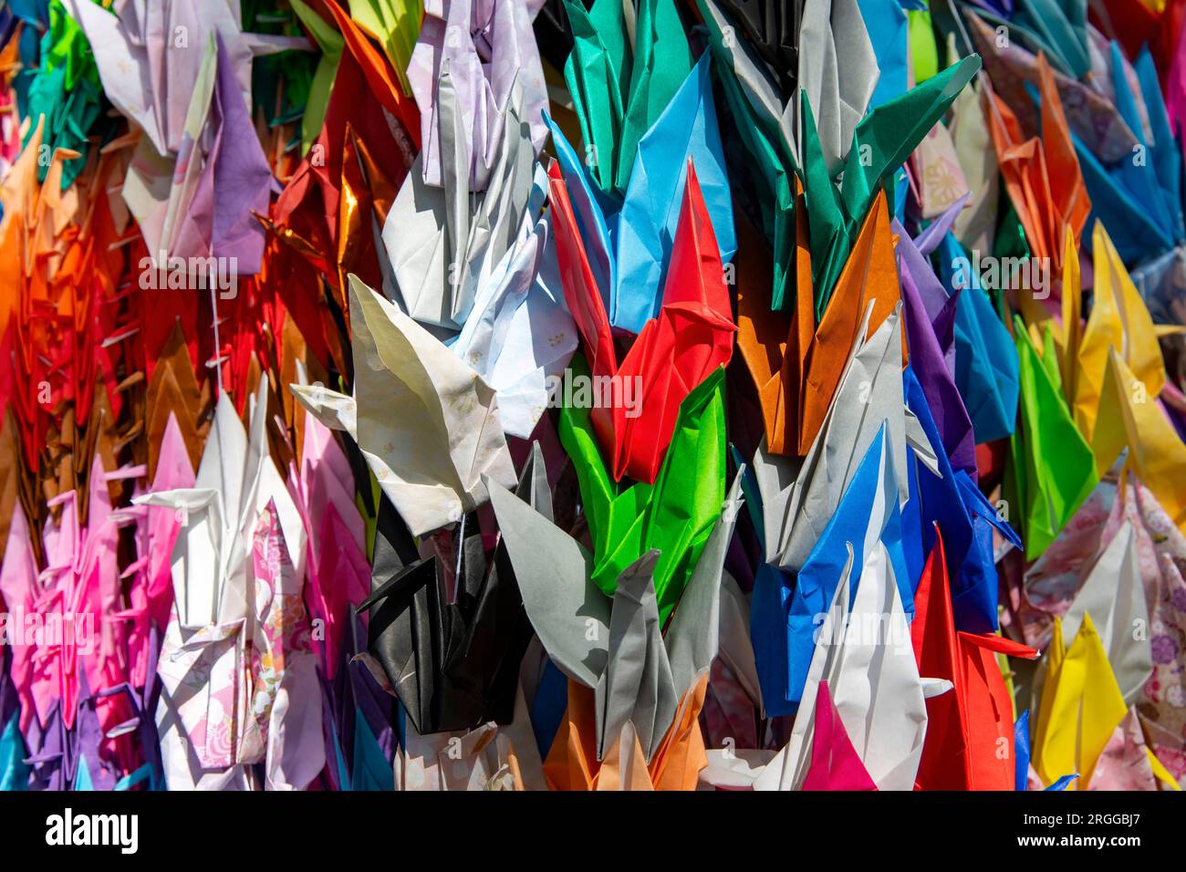 Bildfüllende Nahaufnahme der farbenfrohen Origami-Papierkraniche, ein traditionelles japanisches Spiel, bei dem aufwendig gestaltetes Papier in viele Formen gefaltet wird Stockfoto