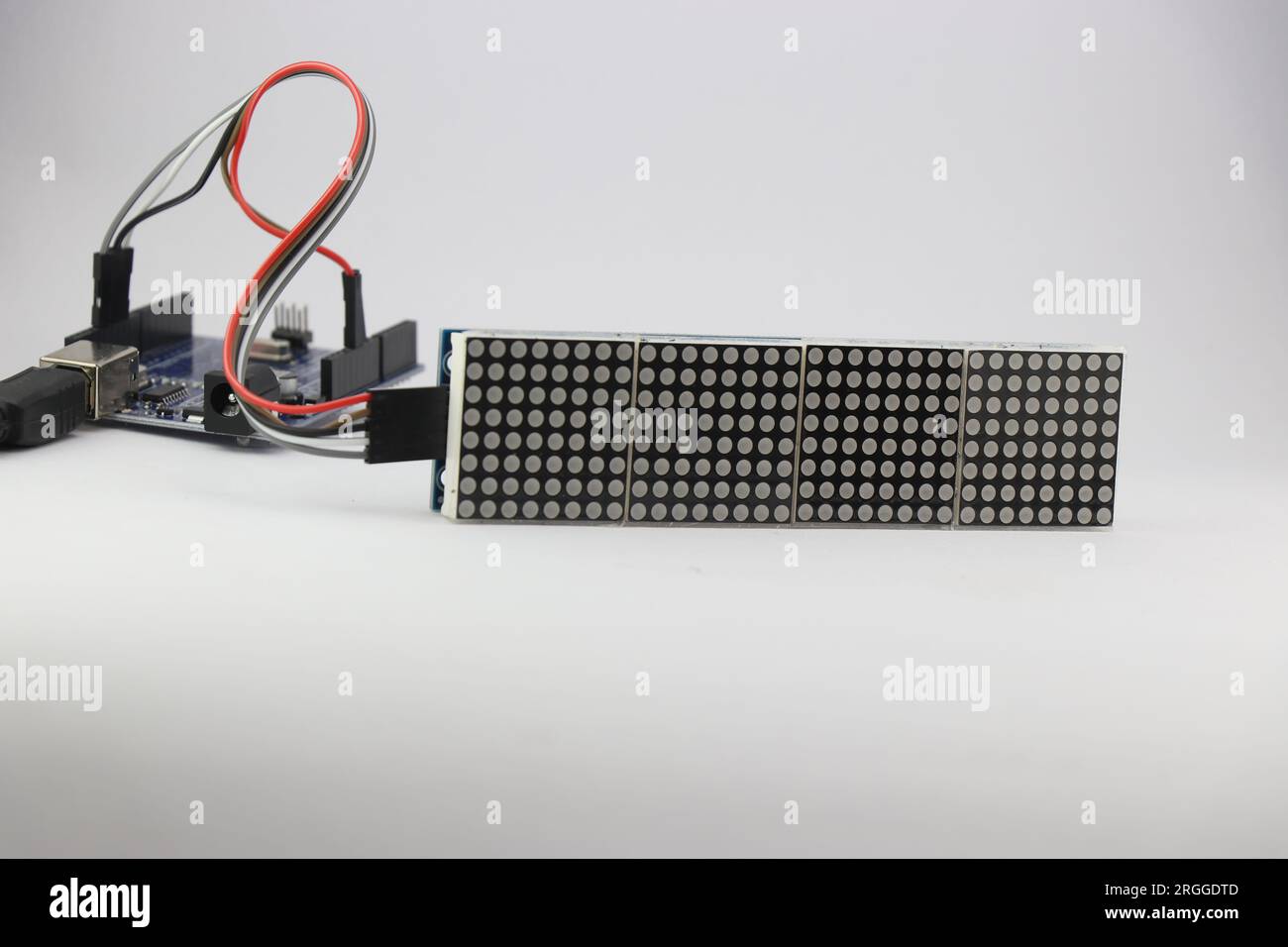 Die LED-Punktmatrixanzeige ist mit einem Mikrocontroller über Überbrückungskabel verbunden, die ein Programm zur Anzeige von Informationen enthalten Stockfoto