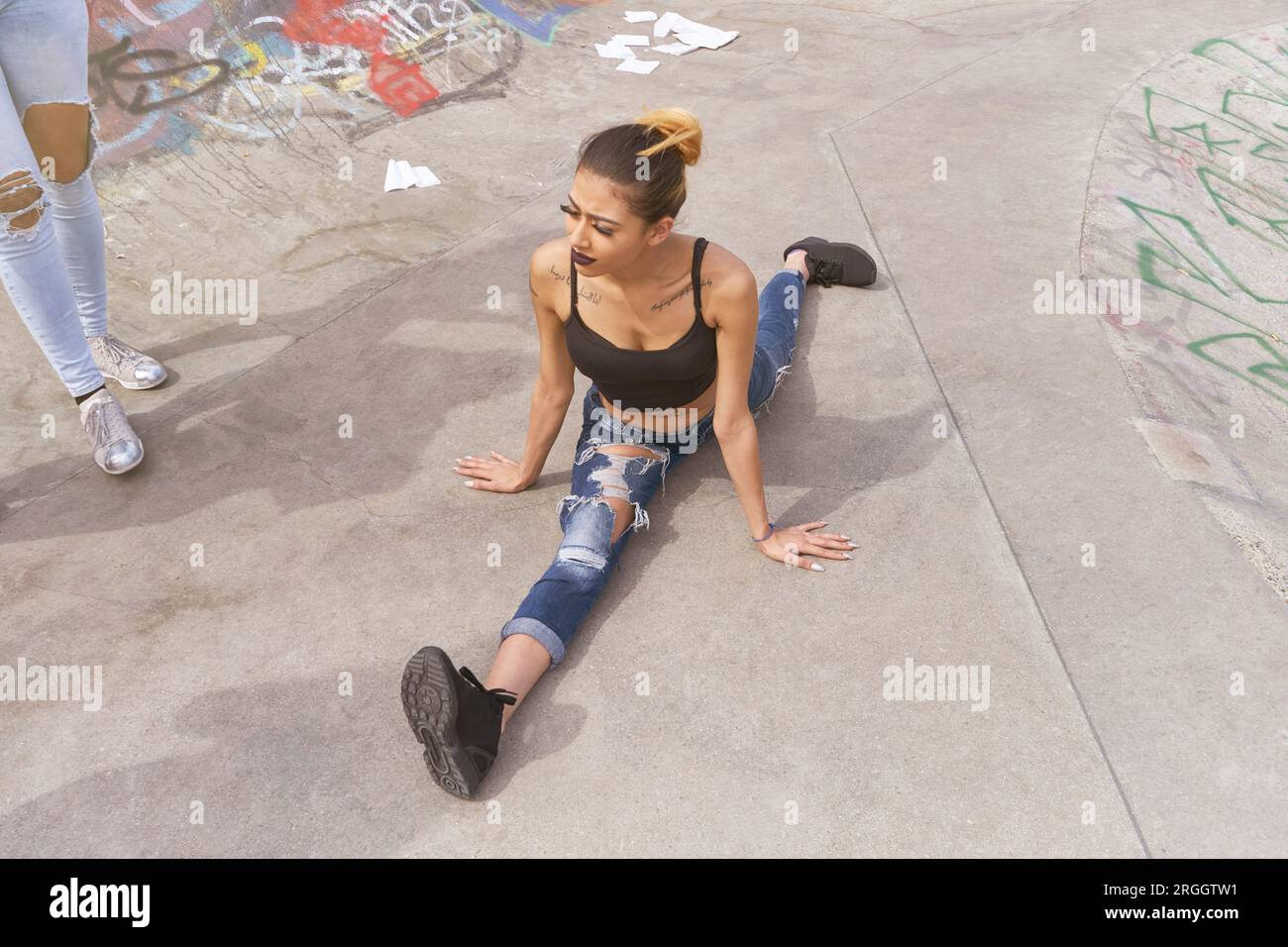 Junge Frau tun Splits Skate Park Stockfoto
