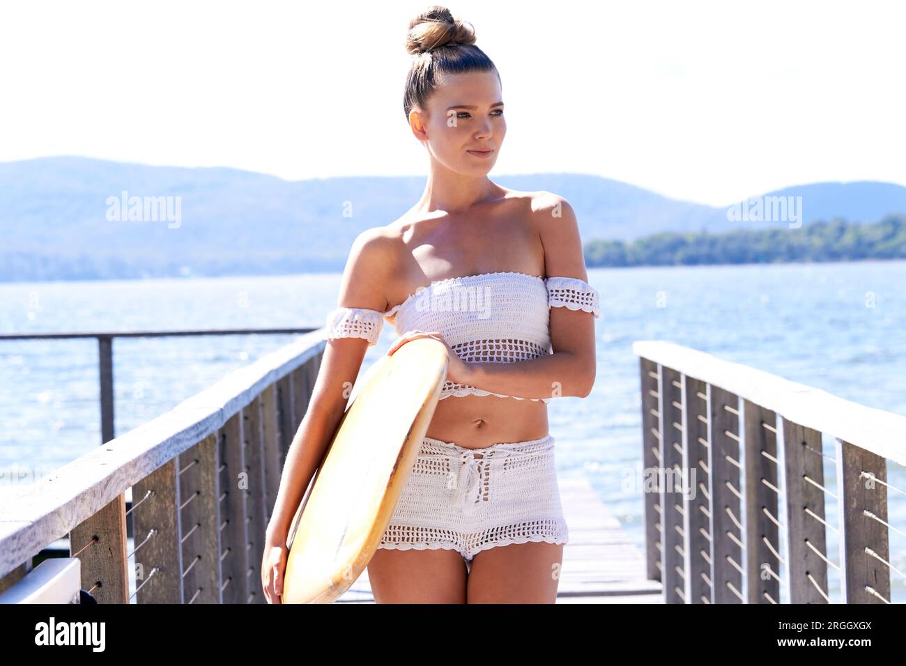 Junge Frau mit Surfbrett auf Pier posing Stockfoto